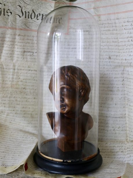 Hand carved bust of an infant in an antique glass dome