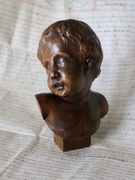 Hand carved bust of an infant in an antique glass dome