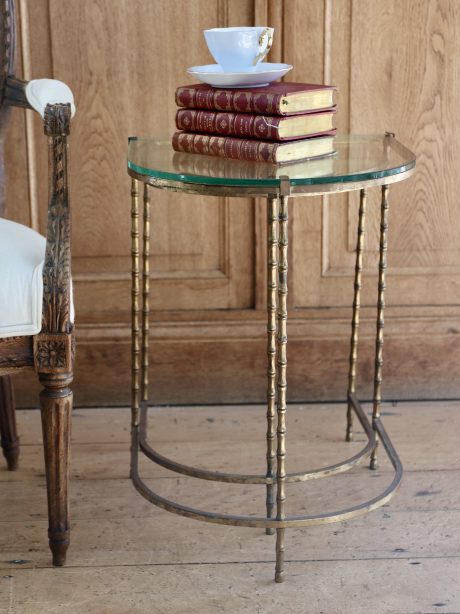 A pair of Hollywood Regency nesting tables in glass and faux bamboo brass