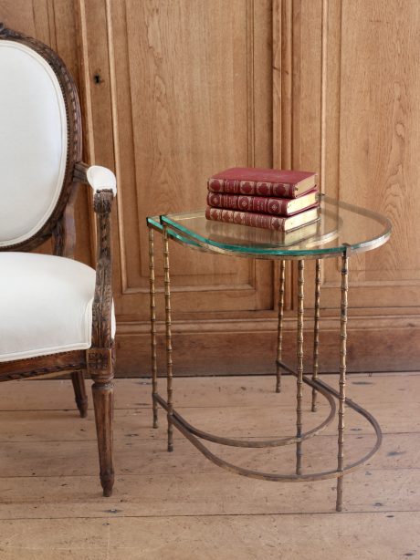 A pair of Hollywood Regency nesting tables in glass and faux bamboo brass