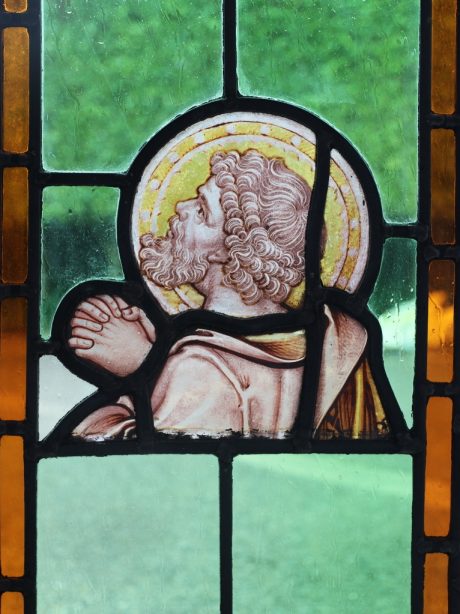 An antique religious stained glass panel of a Saint